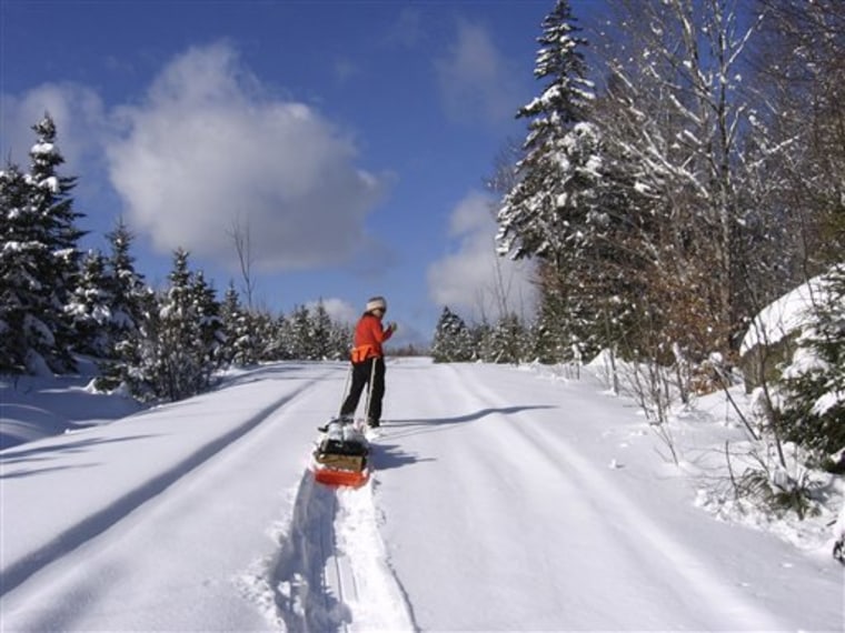Lynn Dombek pauses while snowshoeing up a hill on snow-covered logging roads in Hancock County, Maine.